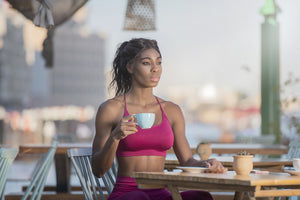 coffee before workout: woman wearing sports attire and holding a cup of coffee